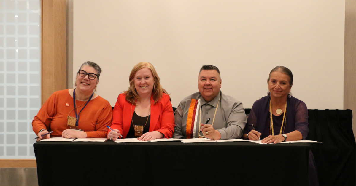 four people signing document at table