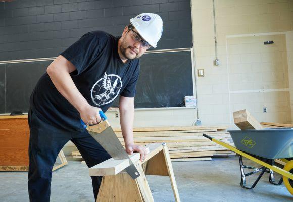 Student using saw to cut through wood