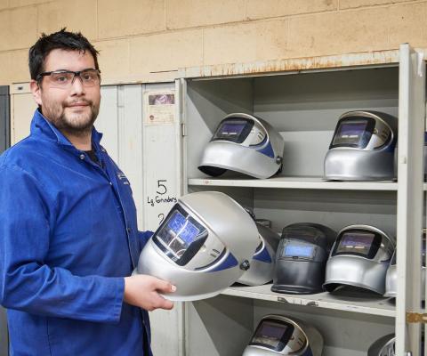 student holding a welding mask