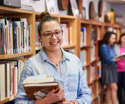 student in front of bookshelf