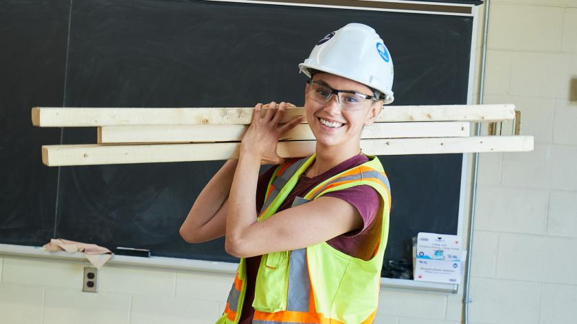 Construction student carrying wood