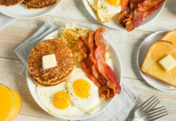 plate of fried eggs, bacon, and pancakes